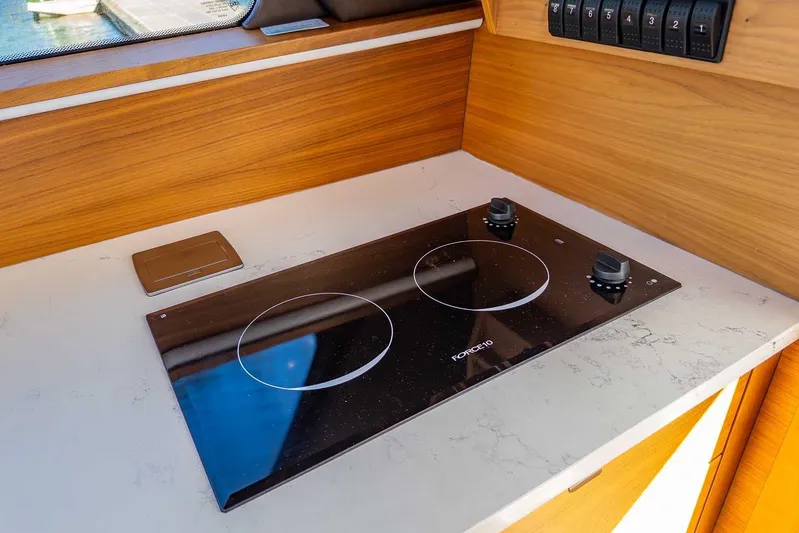  Yacht Photos Pics Modern kitchen cooktop on 2020 Coastal Craft 33 Express yacht, featuring sleek design and wood accents.