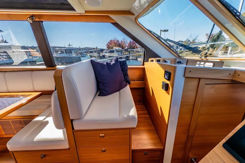  Yacht Photos Pics 2020 Coastal Craft 33 Express interior with white seating, wooden accents, and marina view.