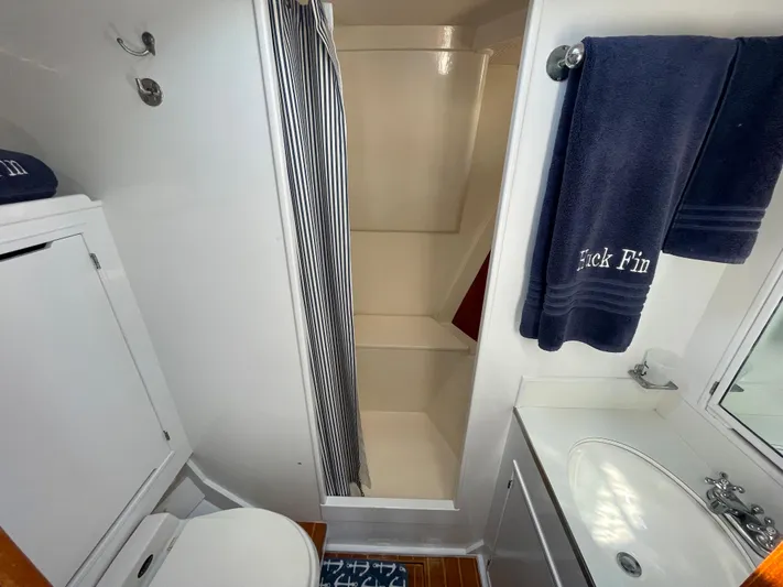 Huck Fin Yacht Photos Pics Bathroom interior of a 1966 Huckins Sportsman boat, featuring shower, sink, and towels.