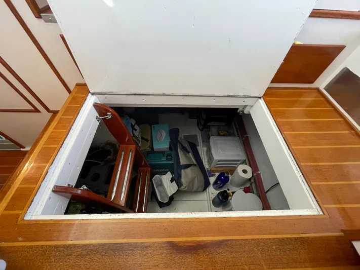 Huck Fin Yacht Photos Pics Storage compartment on a 1966 Huckins Sportsman boat, featuring wooden flooring and various stored items.
