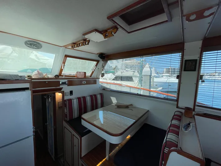 Huck Fin Yacht Photos Pics Interior of a 1966 Huckins Sportsman boat with dining area and striped seating.