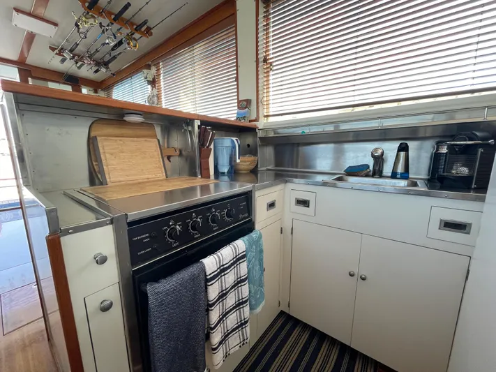Huck Fin Yacht Photos Pics 1966 Huckins Sportsman boat kitchen with stove, cabinets, and striped rug.