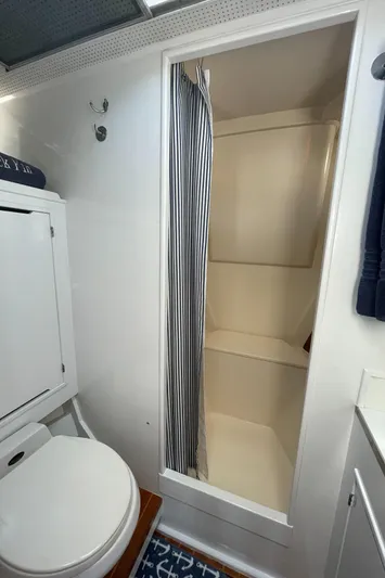 Huck Fin Yacht Photos Pics 1966 Huckins Sportsman bathroom with shower, toilet, and nautical decor.