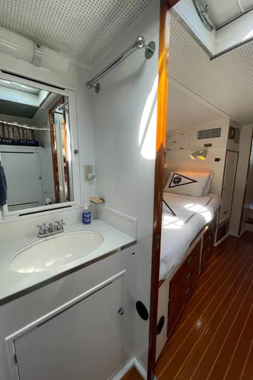 Huck Fin Yacht Photos Pics 1966 Huckins Sportsman interior with wooden flooring, compact bathroom, and cozy sleeping area.