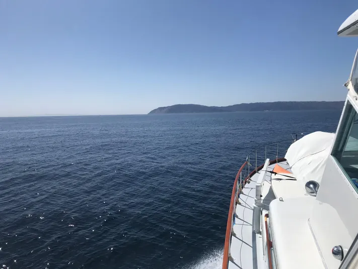 Huck Fin Yacht Photos Pics 1966 Huckins Sportsman boat cruising on open sea with distant coastline.