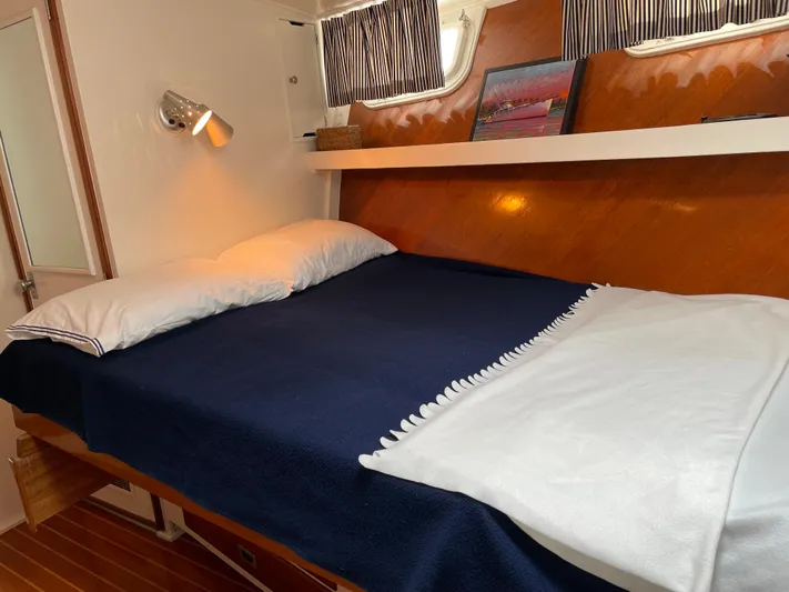 Huck Fin Yacht Photos Pics 1966 Huckins Sportsman cabin with cozy bed, wooden accents, and nautical decor.