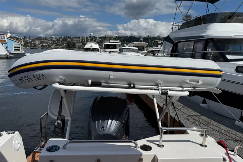  Yacht Photos Pics 2024 Ranger Tugs R-25 with inflatable boat on top, docked in a marina.