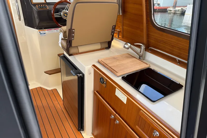  Yacht Photos Pics 2024 Ranger Tugs R-25 interior with kitchenette, wooden cabinetry, and helm station.