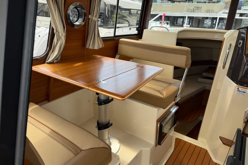  Yacht Photos Pics 2024 Ranger Tugs R-25 interior with wood table and beige seating.