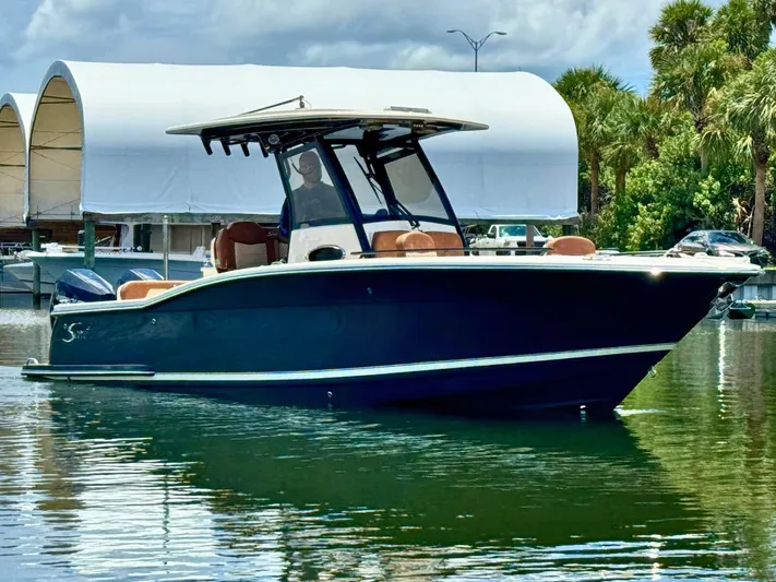  Yacht Photos Pics 2024 Scout 277 LXF boat on calm water with covered docks in background.