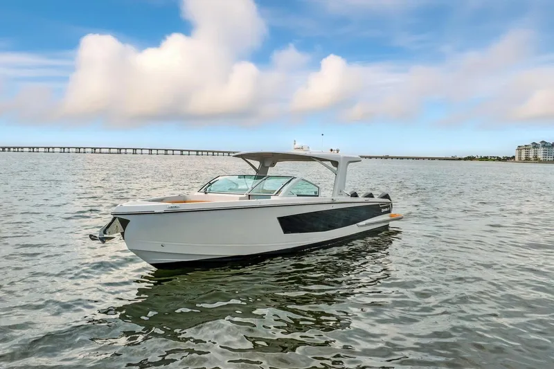  Yacht Photos Pics 2021 Aviara AV36 OB boat on calm water with a scenic bridge and cloudy sky.