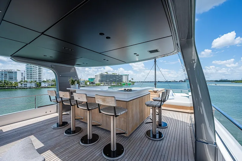 The Wolf Yacht Photos Pics Luxurious 2023 Sanlorenzo SD118 yacht deck with bar, overlooking serene waterfront views.
