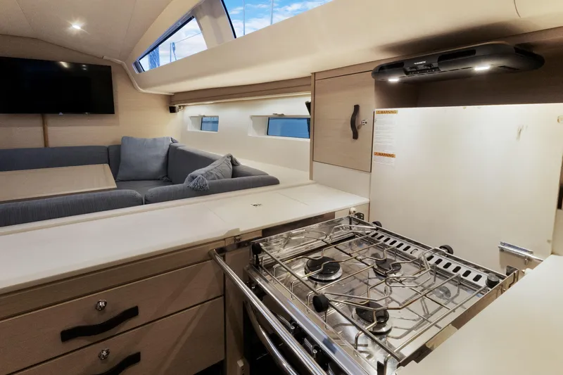 Beatrice Yacht Photos Pics Modern interior of 2021 Jeanneau Sun Odyssey 51 Performance yacht with kitchen and seating area.