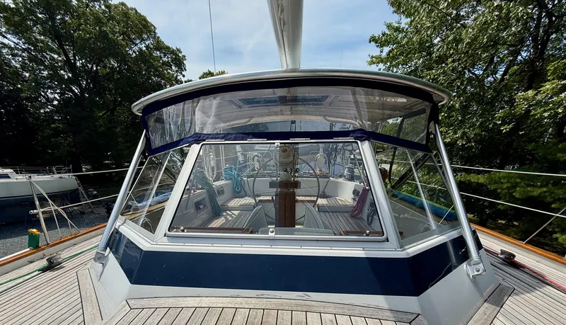 Pegasus Yacht Photos Pics 1984 Hallberg-Rassy 49 sailboat cockpit with clear canopy, surrounded by lush greenery.