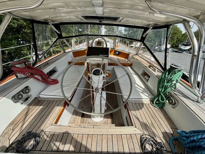 Pegasus Yacht Photos Pics 1984 Hallberg-Rassy 49 yacht cockpit with steering wheel, ropes, and wooden deck.
