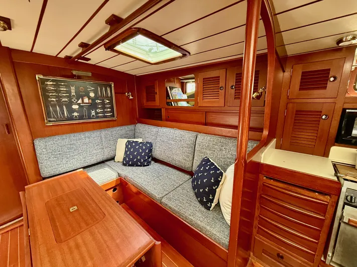 Pegasus Yacht Photos Pics Cozy interior of 1984 Hallberg-Rassy 49 yacht with wooden finish and blue cushions.
