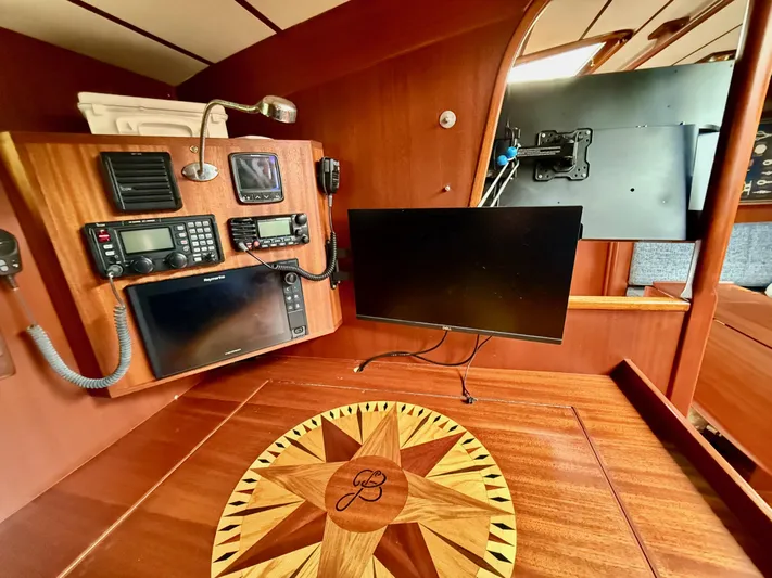 Pegasus Yacht Photos Pics Navigation station of 1984 Hallberg-Rassy 49 yacht with communication equipment and wooden compass design.
