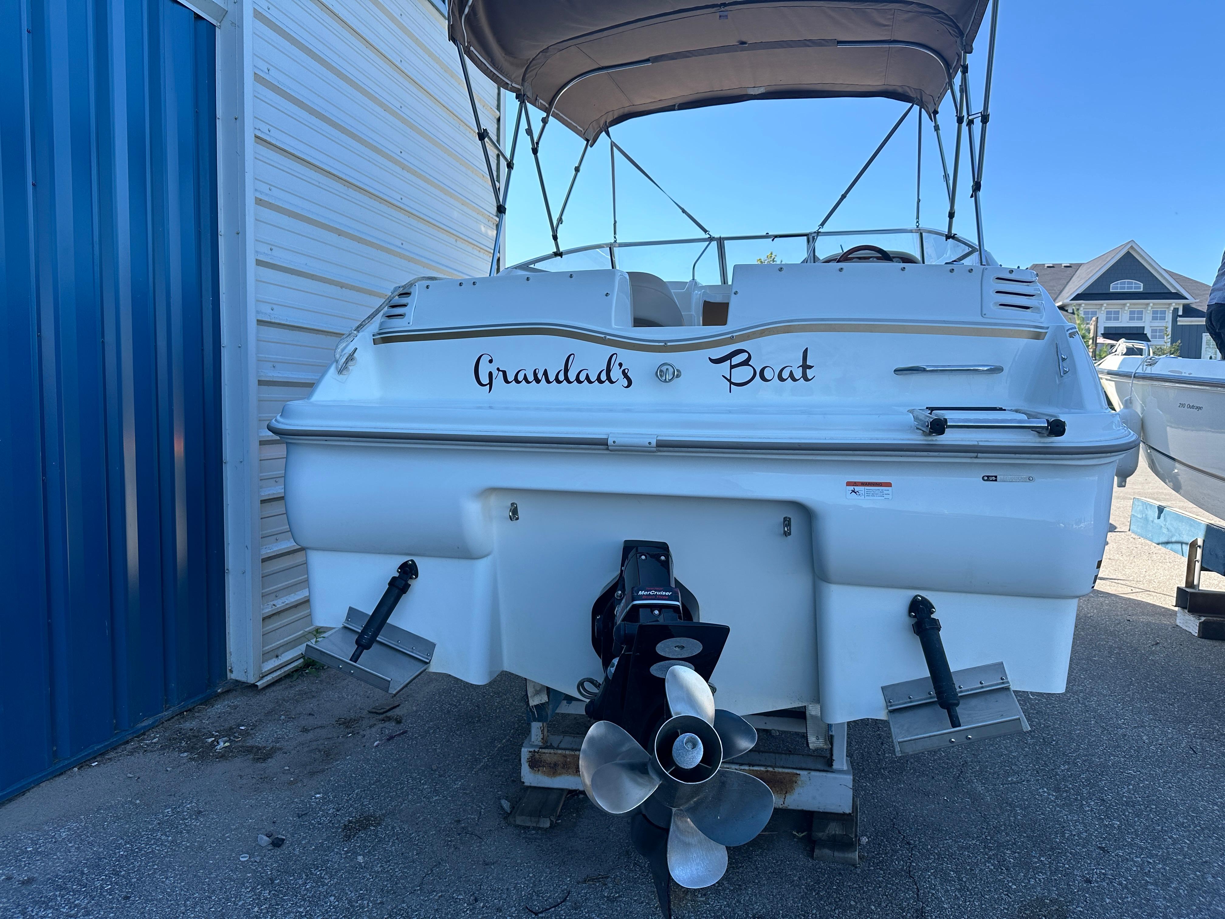 2004 Larson Cabrio 220 boat named "Grandad's Boat" docked near a blue building.