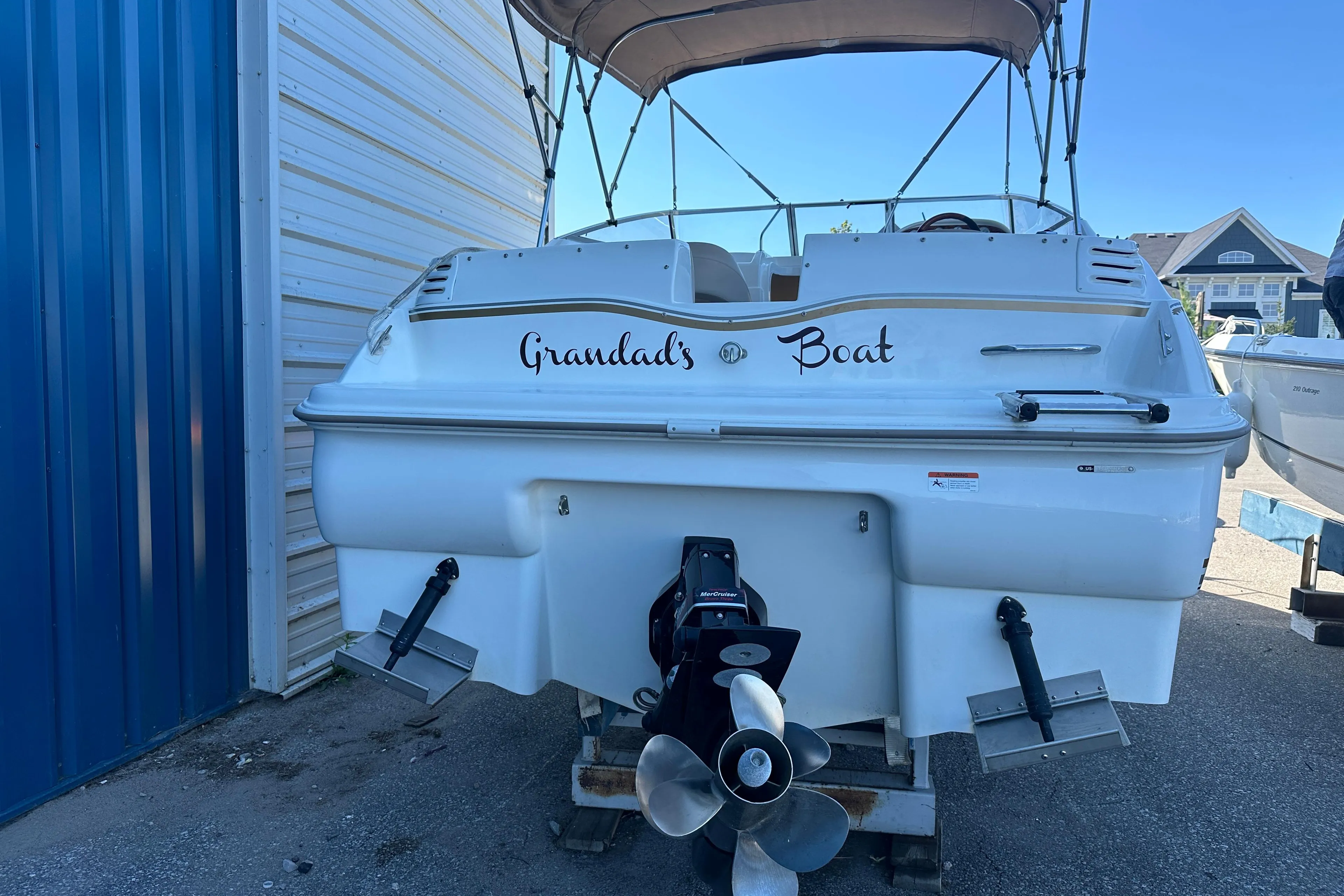 2004 Larson Cabrio 220 boat named "Grandad's Boat" docked near a blue building.