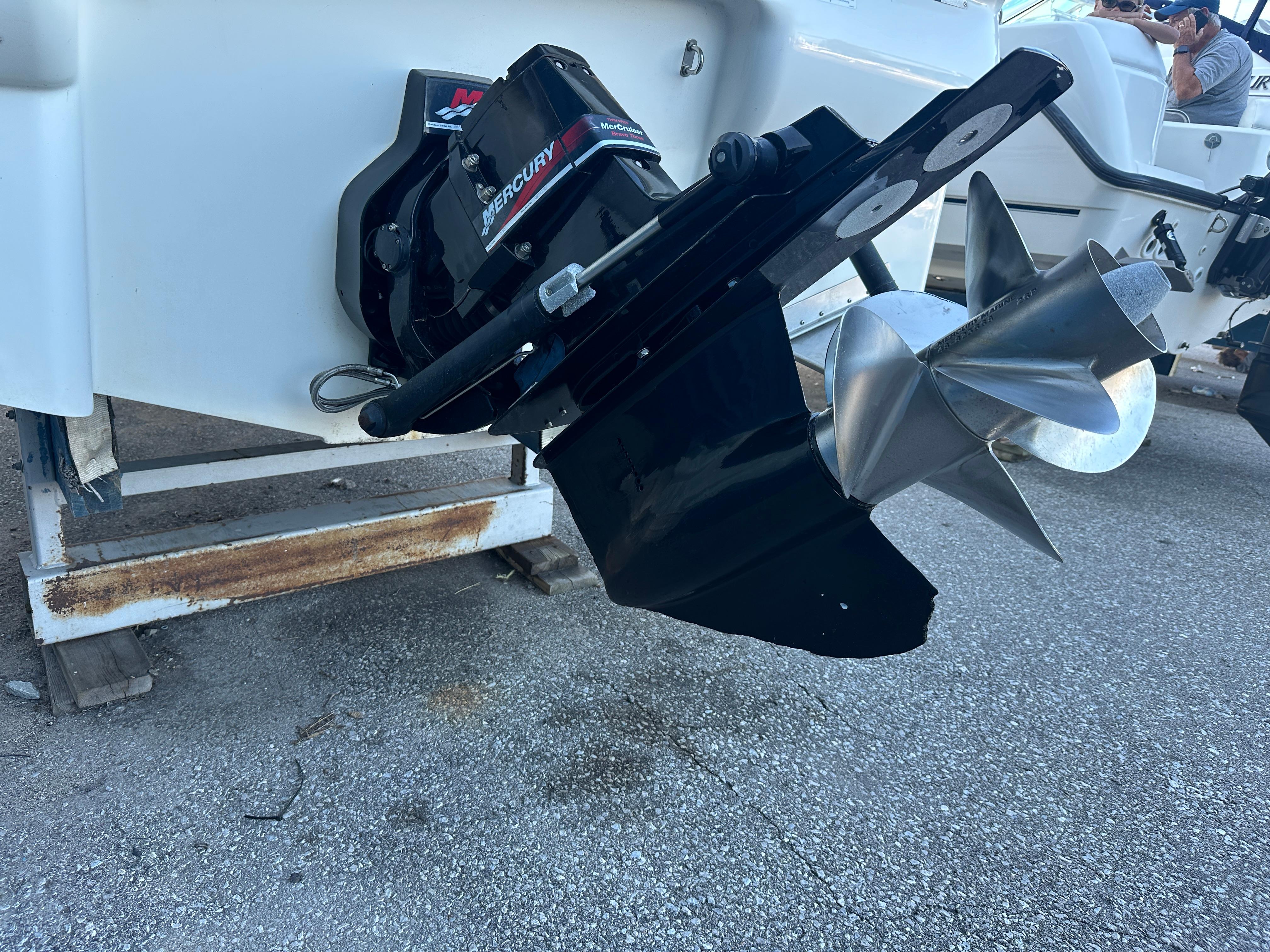 2004 Larson Cabrio 220 boat with Mercury outboard motor and propeller on display.