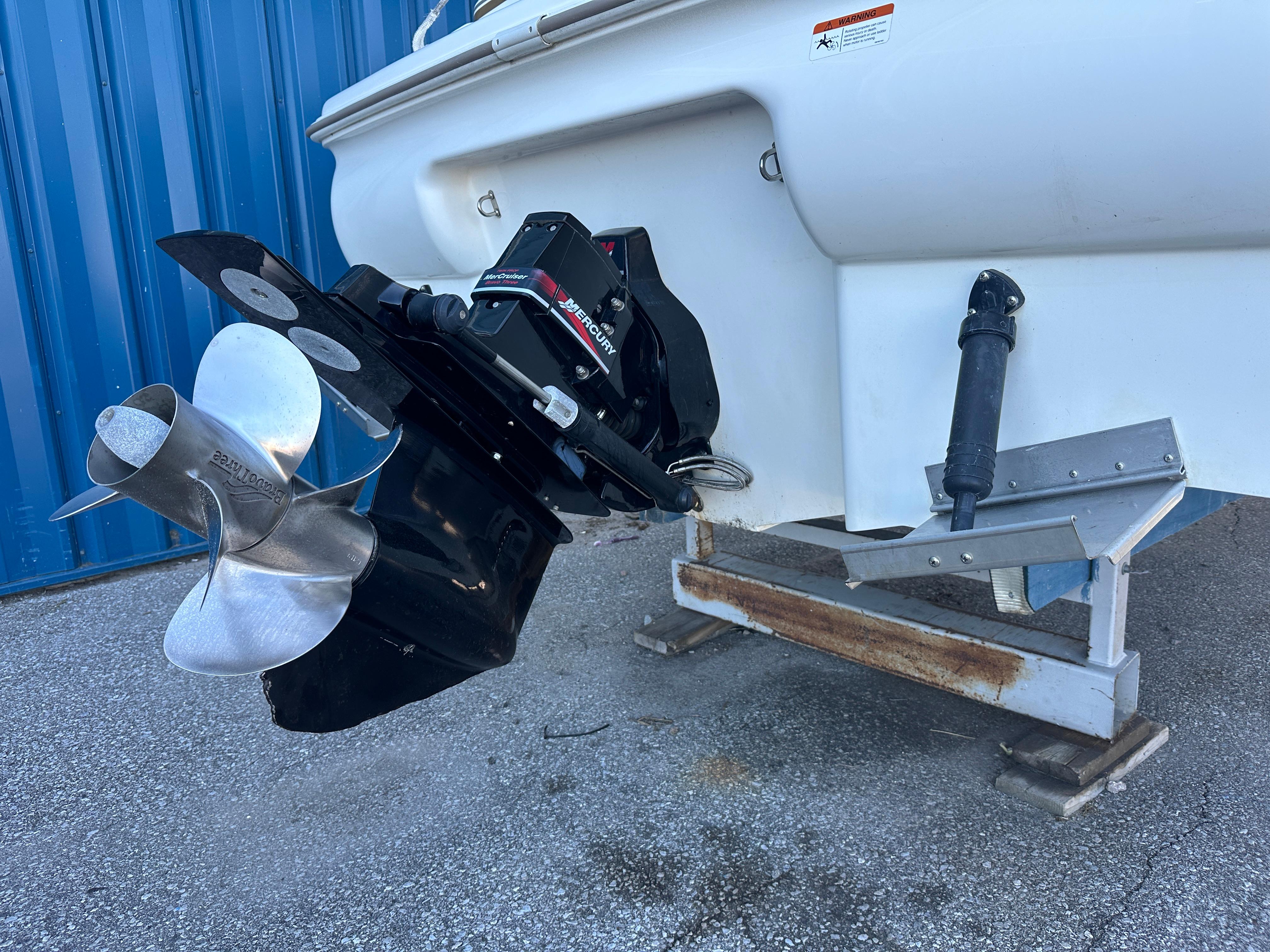 2004 Larson Cabrio 220 boat stern with propeller and outdrive, parked on a trailer.