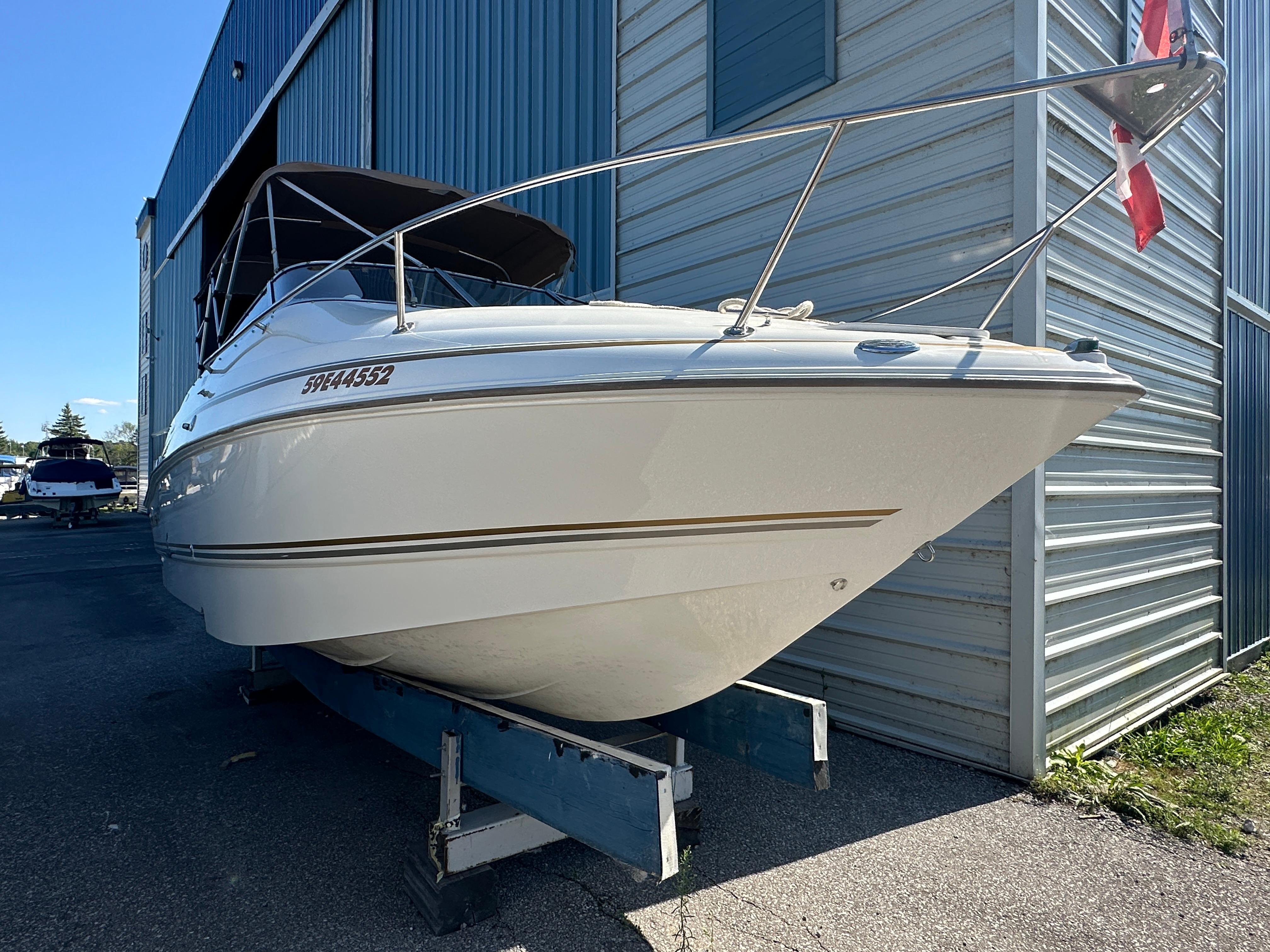 2004 Larson Cabrio 220 boat docked outside a metal building.