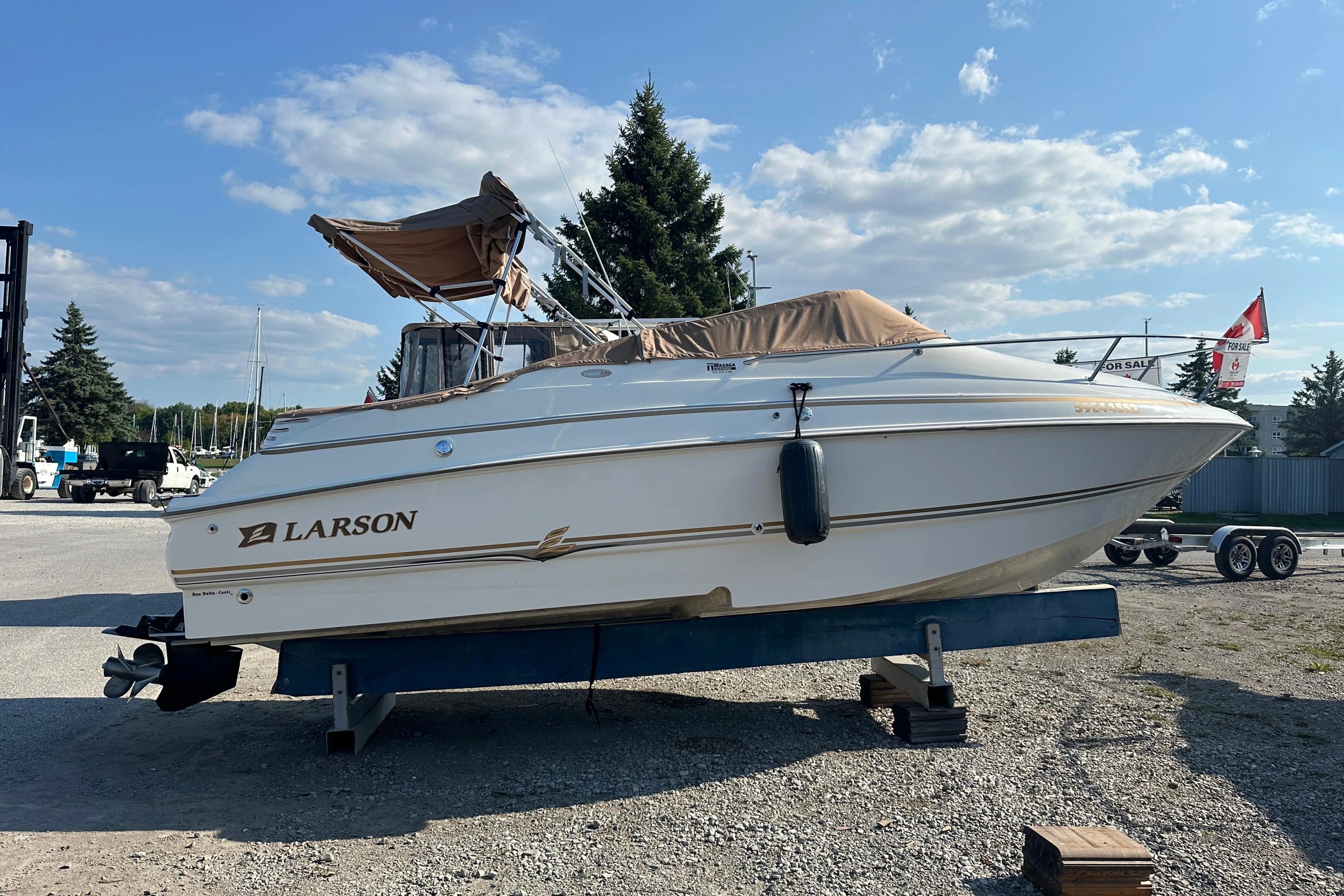 2004 Larson Cabrio 220 boat on trailer, parked outdoors under a clear sky.