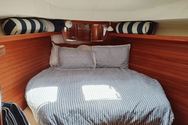  Yacht Photos Pics Cozy cabin interior of 2009 Hunter 50 Center Cockpit with striped bedding and wooden paneling.