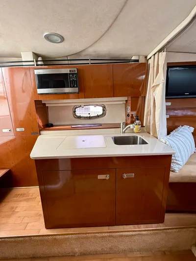 Just Us Yacht Photos Pics 2010 Sea Ray 310 Sundancer interior kitchen with sink, microwave, and wooden cabinetry.