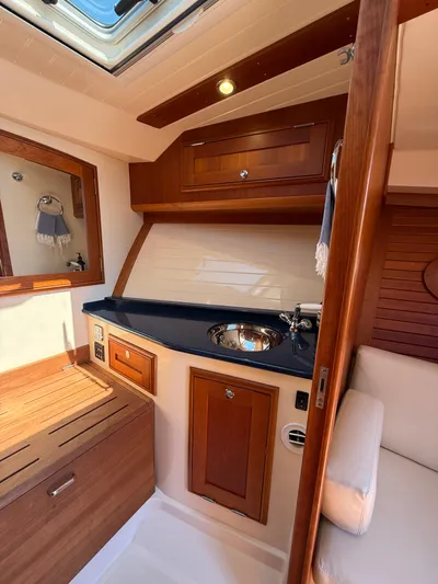 Pampelonne Yacht Photos Pics Interior of 2018 Hinckley 34 Runabout, featuring elegant wood cabinetry and a sleek sink area.