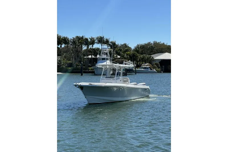  Yacht Photos Pics 2017 Edgewater 318CC boat cruising on a sunny day near palm trees and docks.
