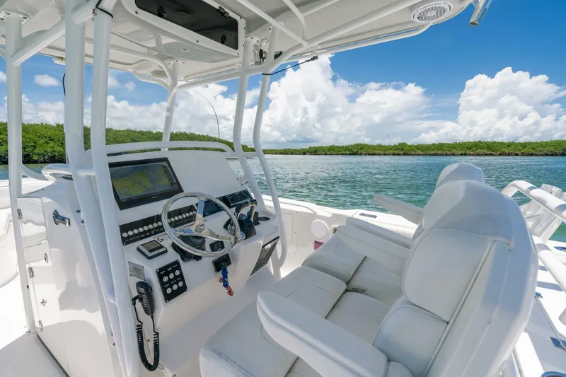 Yacht Photos Pics 2017 Edgewater 318CC boat interior with steering wheel, controls, and seating on a sunny day.