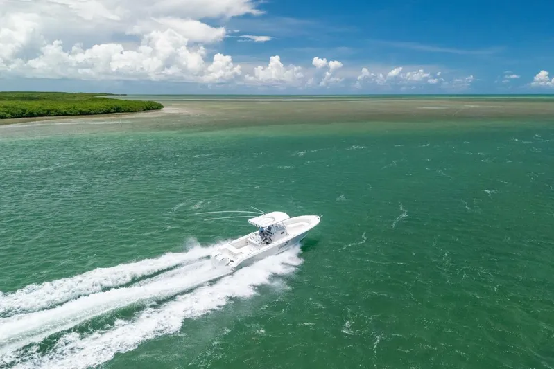  Yacht Photos Pics Edgewater 318CC 2017 boat cruising on turquoise waters under a clear blue sky.