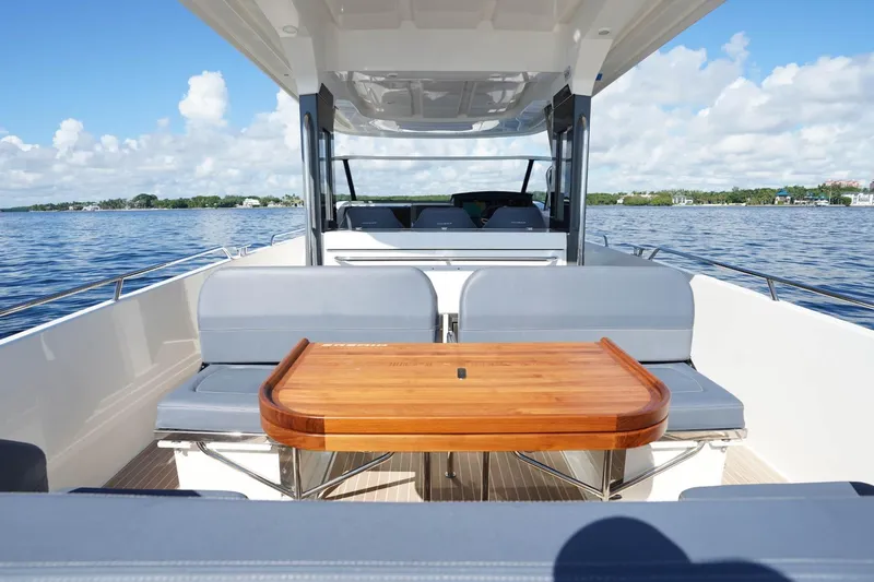 T/t Sophia Yacht Photos Pics 2022 Nimbus T11 boat interior with wooden table and gray seating on a sunny day.
