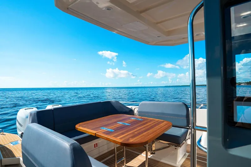 T/t Sophia Yacht Photos Pics Luxurious 2022 Nimbus T11 boat interior with ocean view, featuring a wooden table and cushioned seating.