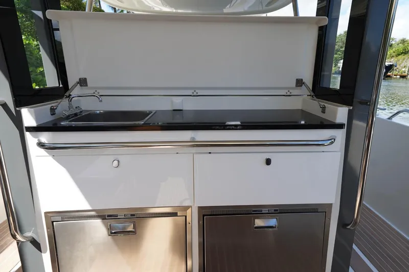 T/t Sophia Yacht Photos Pics Outdoor kitchenette on 2022 Nimbus T11 boat with sink and storage compartments.