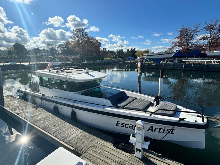 Escape Artist Yacht Photos Pics Axopar 37 Cross Cabin BRABUS 2020 docked, sunny day, calm water, "Escape Artist" on side.