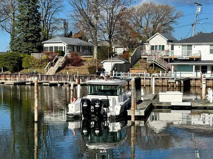 Escape Artist Yacht Photos Pics Axopar 37 Cross Cabin BRABUS 2020 docked at a serene waterfront with houses in the background.