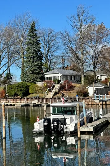 Escape Artist Yacht Photos Pics 2020 Axopar 37 Cross Cabin BRABUS docked by a lakeside house in a serene setting.