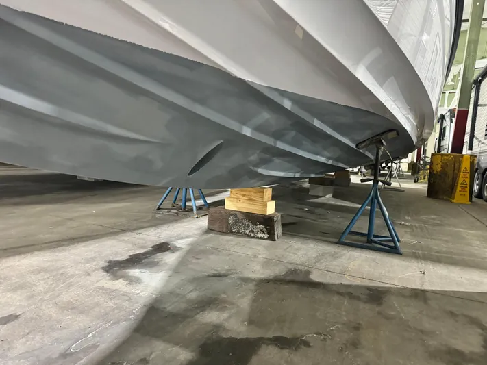 Escape Artist Yacht Photos Pics 2020 Axopar 37 Cross Cabin BRABUS boat hull on stands in a workshop.