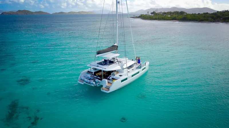Karma Yacht Photos Pics 2020 Lagoon 50 catamaran sailing in clear turquoise waters near a tropical island.