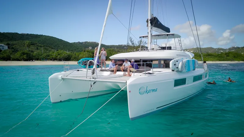 Karma Yacht Photos Pics 2020 Lagoon 50 catamaran anchored in turquoise waters near a tropical beach.