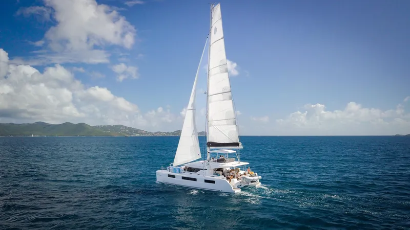 Karma Yacht Photos Pics 2020 Lagoon 50 catamaran sailing on open sea under clear blue sky.