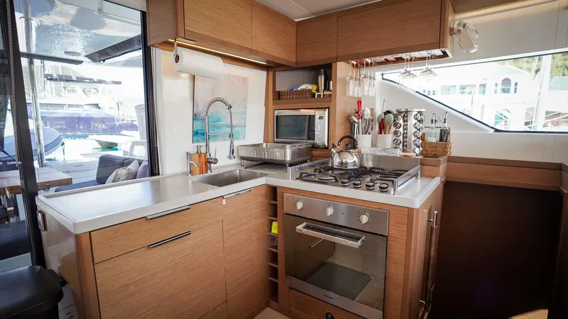 Karma Yacht Photos Pics Modern kitchen interior on 2020 Lagoon 50 yacht, featuring sleek appliances and wooden cabinetry.