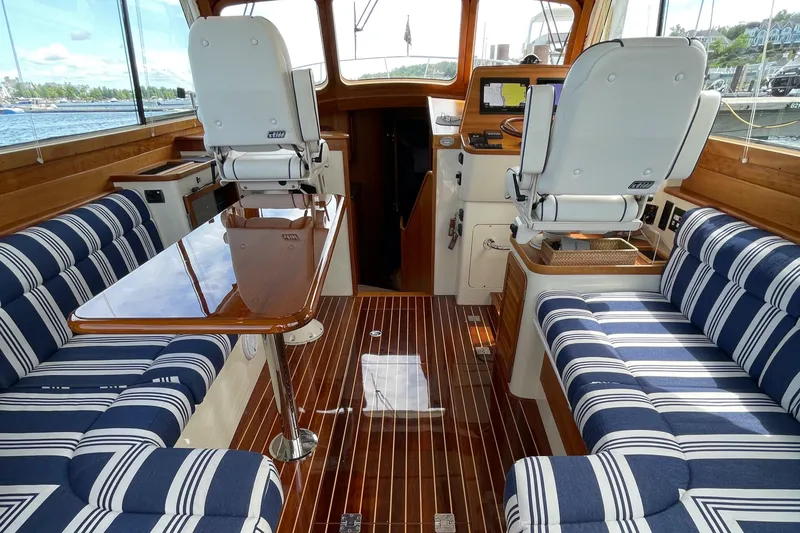 VII Yacht Photos Pics Interior of 2007 Hinckley Talaria 44 Flybridge with striped seating and wooden flooring.