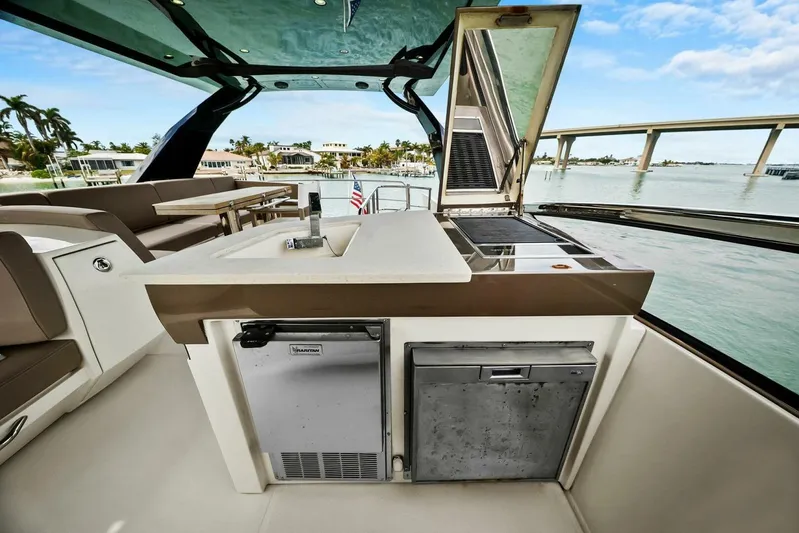 7th Heaven Yacht Photos Pics 2014 Marquis 630 Sport Yacht outdoor kitchen with sink and grill, overlooking serene waterfront.