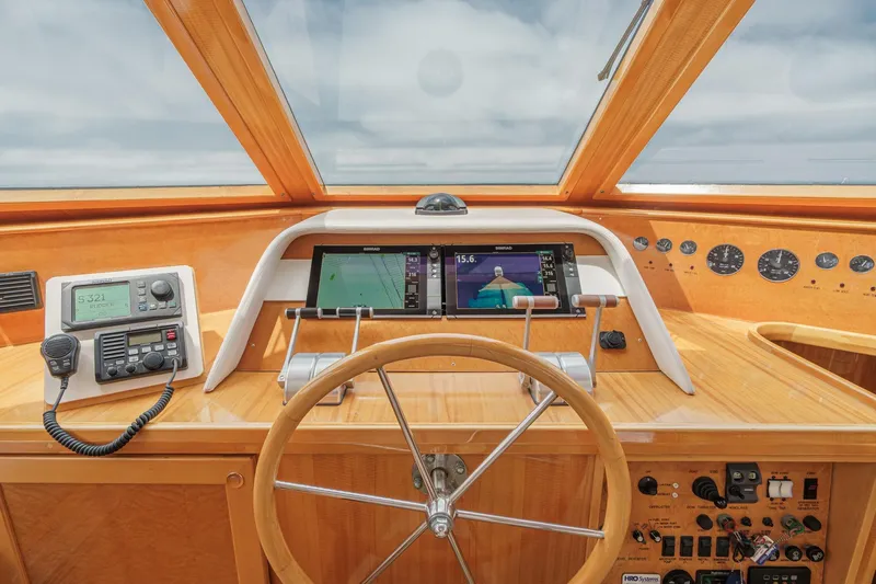 Sweet Seas Yacht Photos Pics Pilothouse of 2001 McKinna 57, featuring navigation screens, controls, and wooden steering wheel.