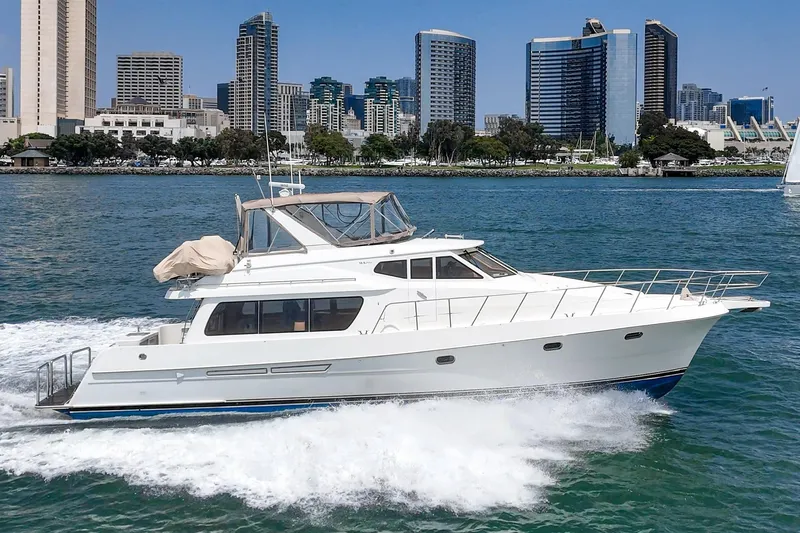 Sweet Seas Yacht Photos Pics 2001 McKinna 57 Pilothouse yacht cruising near city skyline on a sunny day.