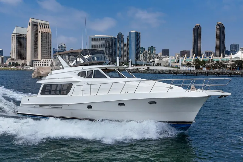 Sweet Seas Yacht Photos Pics 2001 McKinna 57 Pilothouse yacht cruising near city skyline on a sunny day.