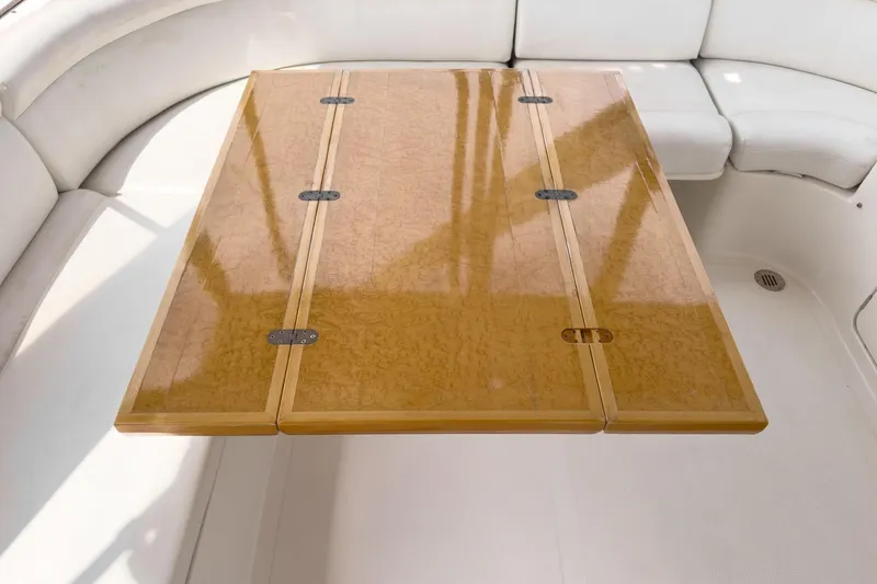 Sweet Seas Yacht Photos Pics Luxurious wooden table on 2001 McKinna 57 Pilothouse yacht, surrounded by white seating.